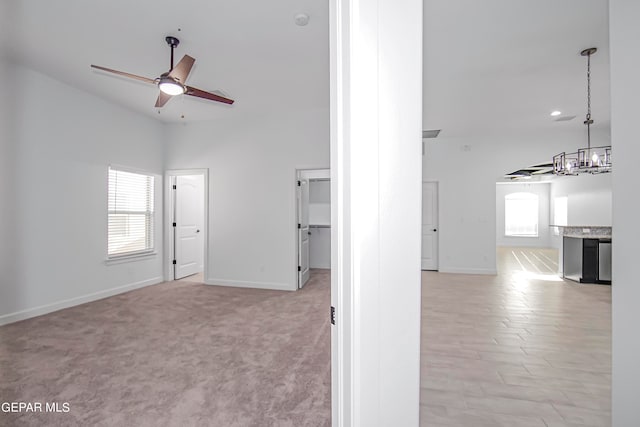 interior space with light carpet and ceiling fan with notable chandelier