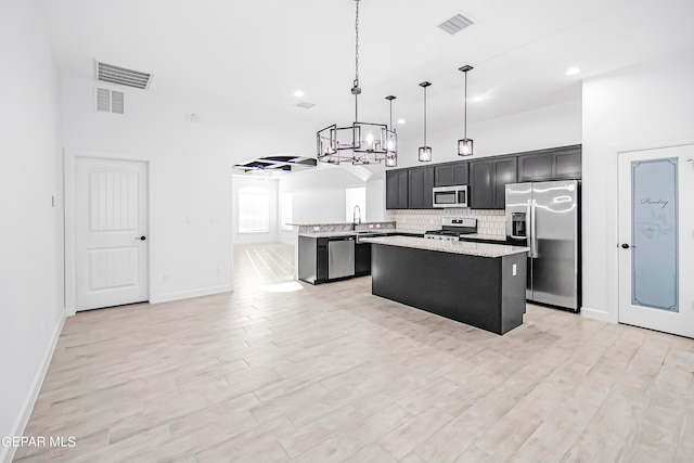 kitchen featuring stainless steel appliances, pendant lighting, light hardwood / wood-style flooring, and a center island