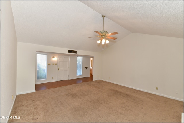 empty room featuring ceiling fan, a textured ceiling, lofted ceiling, and carpet flooring