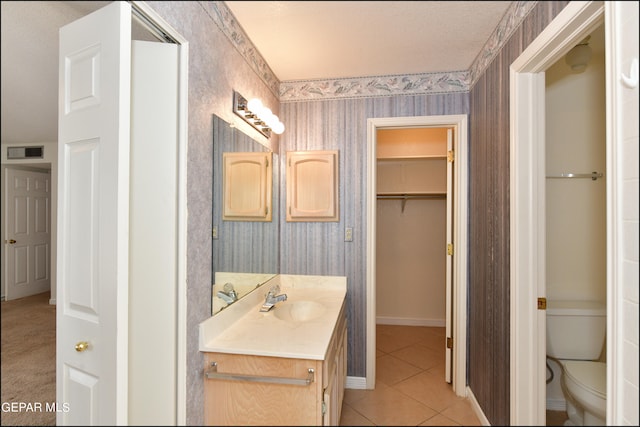 bathroom featuring tile patterned flooring, a textured ceiling, vanity, and toilet