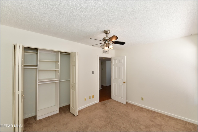 unfurnished bedroom featuring a textured ceiling, ceiling fan, a closet, and light colored carpet