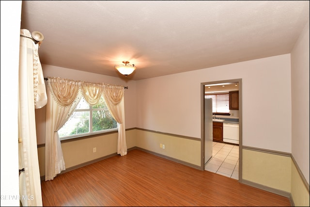 empty room featuring light wood-type flooring and a textured ceiling