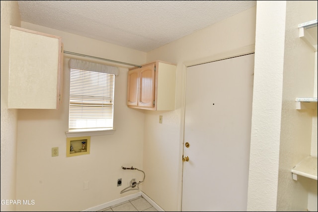 laundry area featuring hookup for a washing machine, hookup for an electric dryer, cabinets, light tile patterned floors, and a textured ceiling