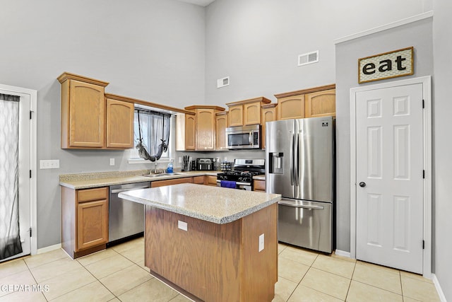 kitchen featuring a center island, stainless steel appliances, sink, light tile patterned flooring, and a high ceiling