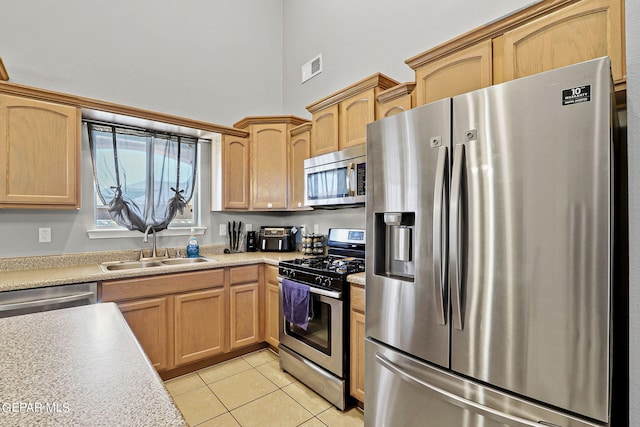 kitchen with appliances with stainless steel finishes, sink, light brown cabinets, and light tile patterned flooring