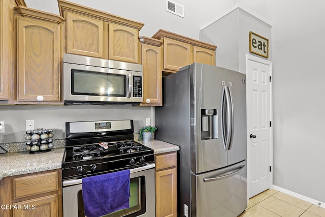 kitchen featuring light tile patterned floors, light stone countertops, and stainless steel appliances