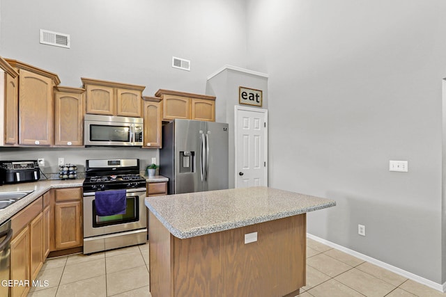 kitchen featuring light stone counters, sink, light tile patterned floors, a kitchen island, and stainless steel appliances