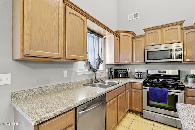 kitchen featuring appliances with stainless steel finishes, light stone countertops, sink, and light tile patterned floors