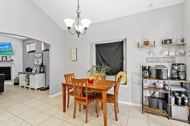 tiled dining space with lofted ceiling, a fireplace, and a chandelier