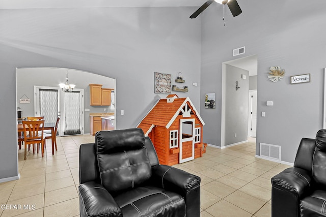 living room featuring ceiling fan with notable chandelier, high vaulted ceiling, and light tile patterned floors