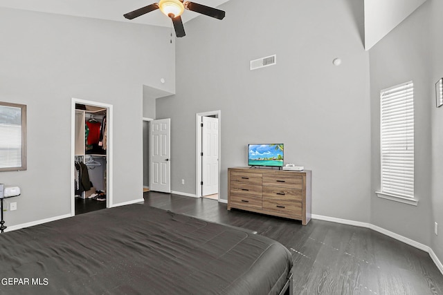 unfurnished bedroom featuring high vaulted ceiling, ceiling fan, a closet, dark hardwood / wood-style flooring, and a walk in closet