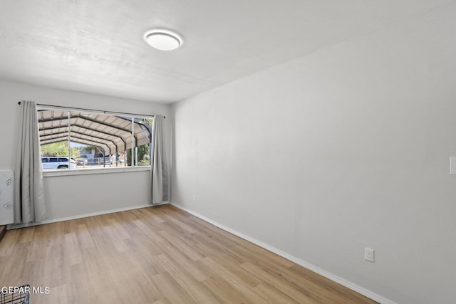 spare room with baseboards and wood finished floors