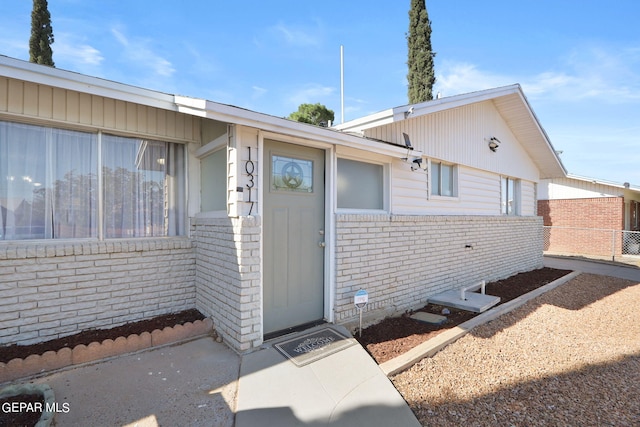 property entrance with fence and brick siding
