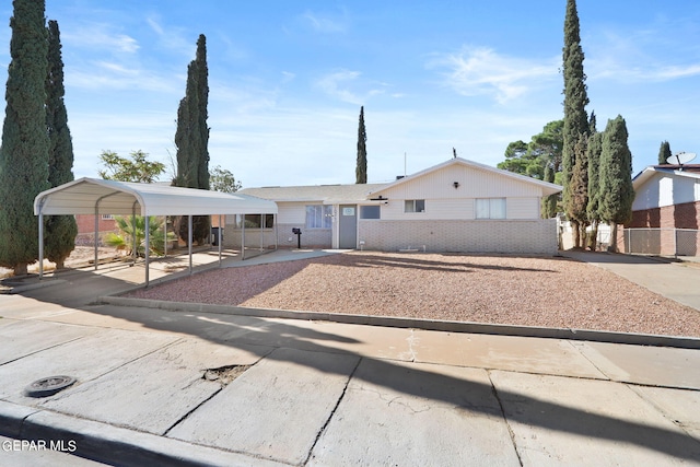 ranch-style home featuring a detached carport, fence, brick siding, and driveway