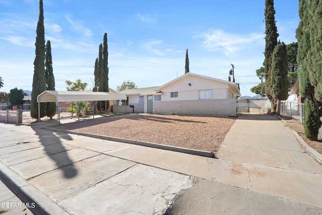 view of front facade with a gate, fence, a carport, brick siding, and driveway