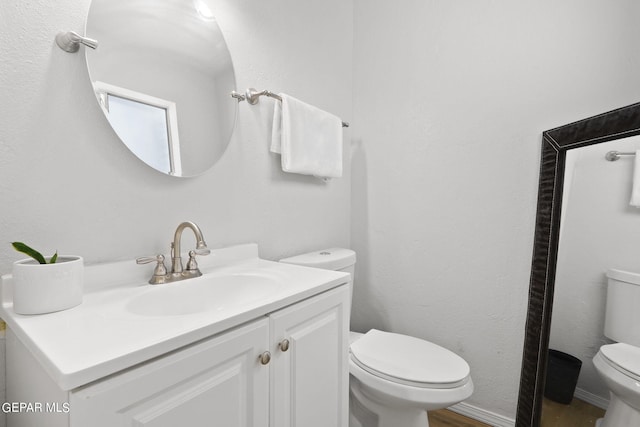 bathroom with toilet, vanity, and wood finished floors
