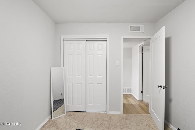 unfurnished bedroom with a closet, visible vents, baseboards, and carpet floors