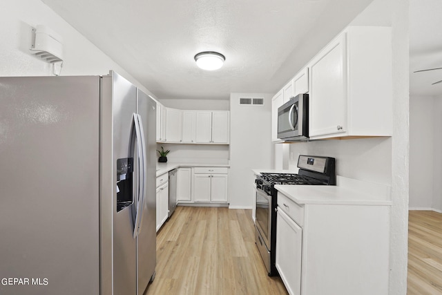 kitchen with light wood finished floors, light countertops, appliances with stainless steel finishes, and visible vents