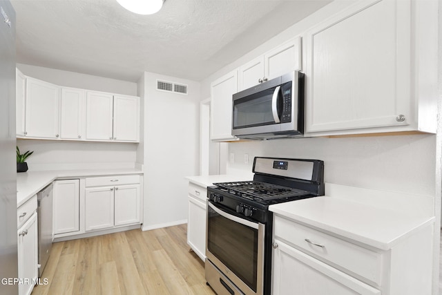 kitchen featuring visible vents, light wood-style flooring, white cabinetry, light countertops, and appliances with stainless steel finishes