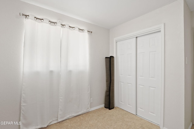 unfurnished bedroom with carpet, a closet, and baseboards