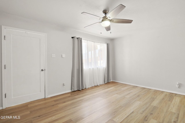 spare room featuring baseboards, ceiling fan, and light wood-type flooring