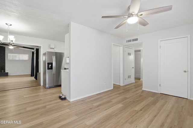 unfurnished living room with baseboards, light wood finished floors, visible vents, and ceiling fan with notable chandelier