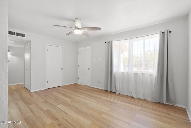 unfurnished bedroom featuring light wood-style flooring, baseboards, a ceiling fan, and visible vents