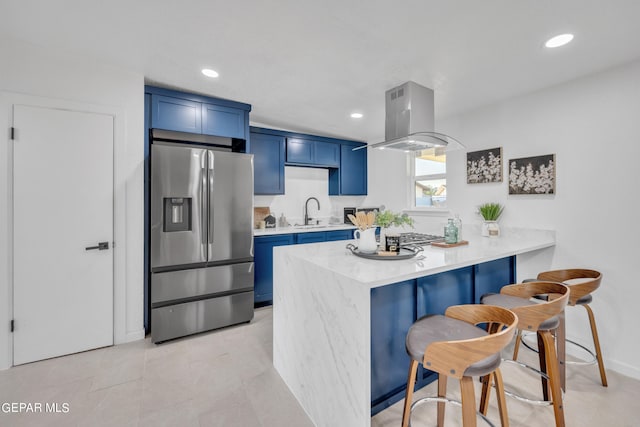 kitchen with blue cabinets, kitchen peninsula, island range hood, stainless steel refrigerator with ice dispenser, and a kitchen breakfast bar