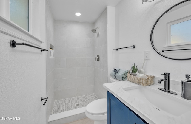 bathroom featuring tiled shower, vanity, and toilet