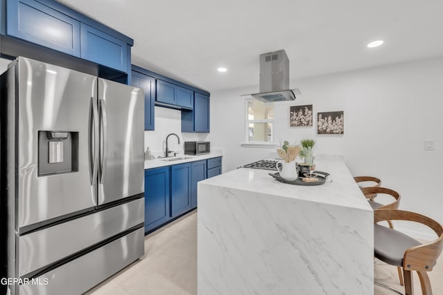 kitchen featuring blue cabinets, stainless steel fridge, exhaust hood, and sink