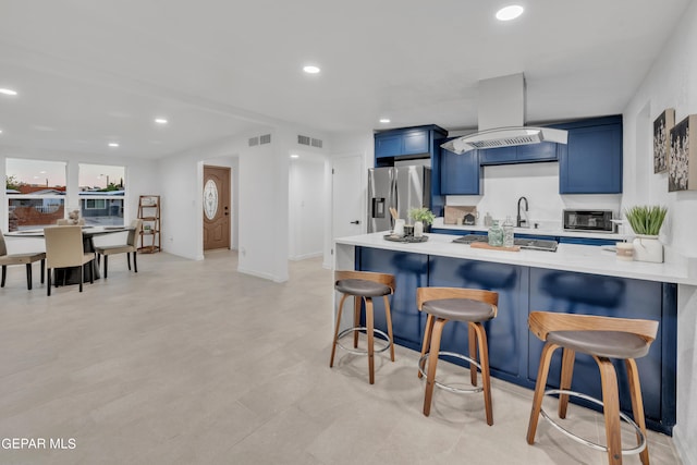 kitchen with stainless steel fridge, premium range hood, kitchen peninsula, a breakfast bar area, and blue cabinets