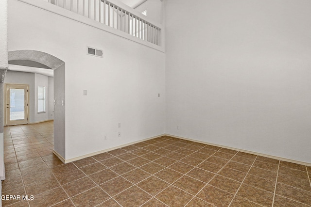 unfurnished room featuring dark tile patterned floors and a high ceiling