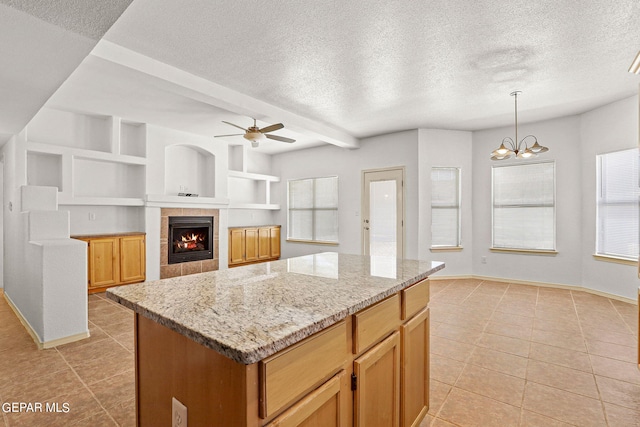 kitchen featuring a wealth of natural light, a center island, hanging light fixtures, and a fireplace