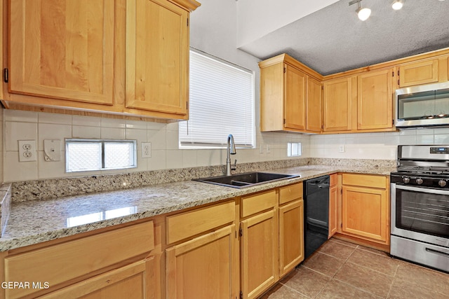 kitchen with dark tile patterned flooring, stainless steel appliances, sink, light stone counters, and a textured ceiling