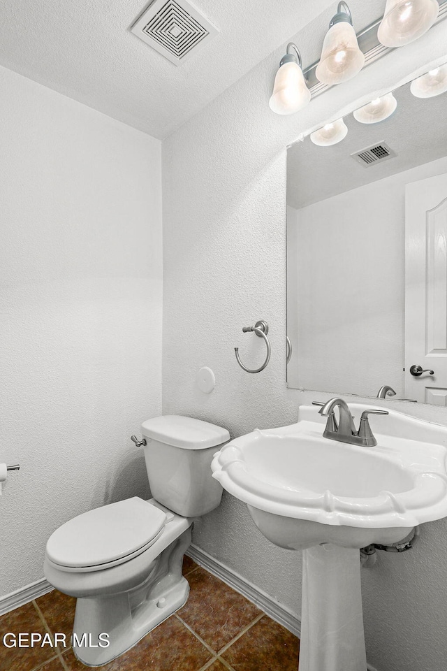 bathroom featuring a textured ceiling, toilet, and tile patterned flooring