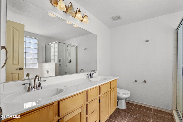 bathroom featuring toilet, tile patterned flooring, vanity, a textured ceiling, and an enclosed shower