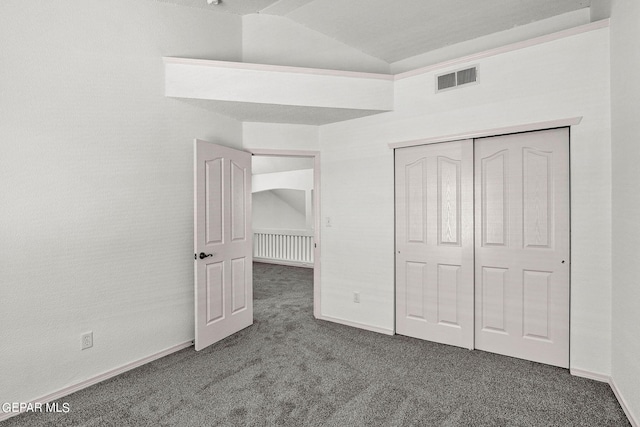 unfurnished bedroom with a closet, lofted ceiling, and dark carpet