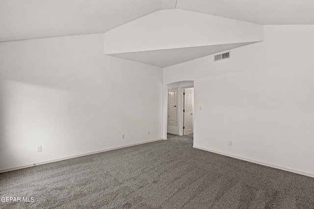 spare room featuring lofted ceiling and dark colored carpet