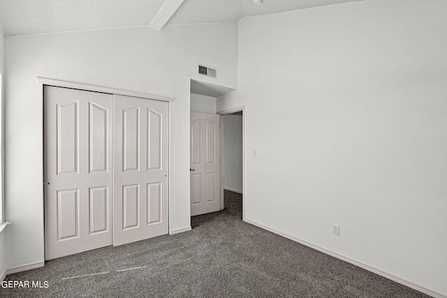 unfurnished bedroom featuring a closet, a textured ceiling, high vaulted ceiling, and dark carpet