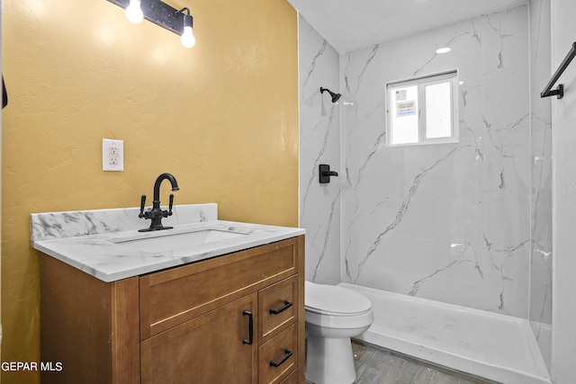 bathroom featuring toilet, vanity, and tiled shower