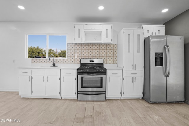 kitchen featuring light hardwood / wood-style floors, sink, backsplash, appliances with stainless steel finishes, and white cabinetry