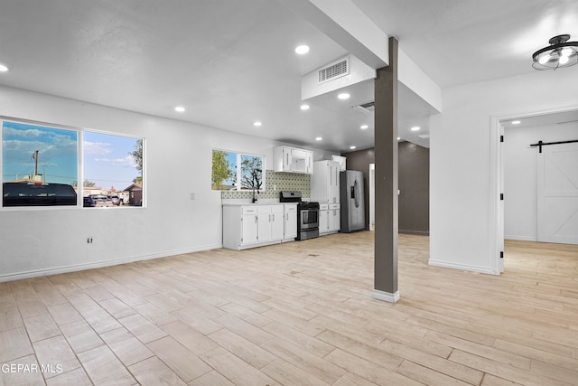 unfurnished living room featuring light hardwood / wood-style floors and a barn door