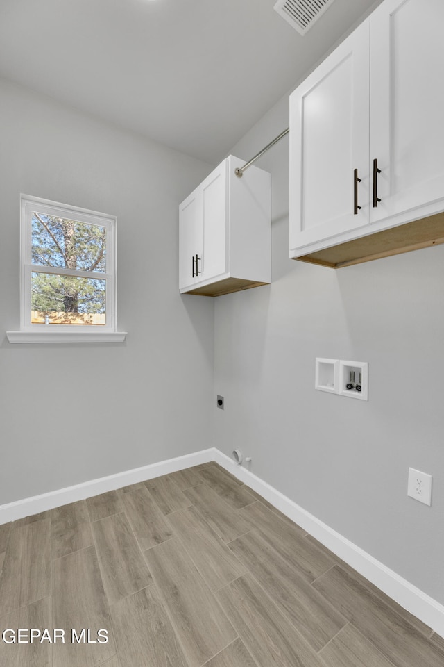 laundry area with hookup for a washing machine, cabinets, light wood-type flooring, and electric dryer hookup