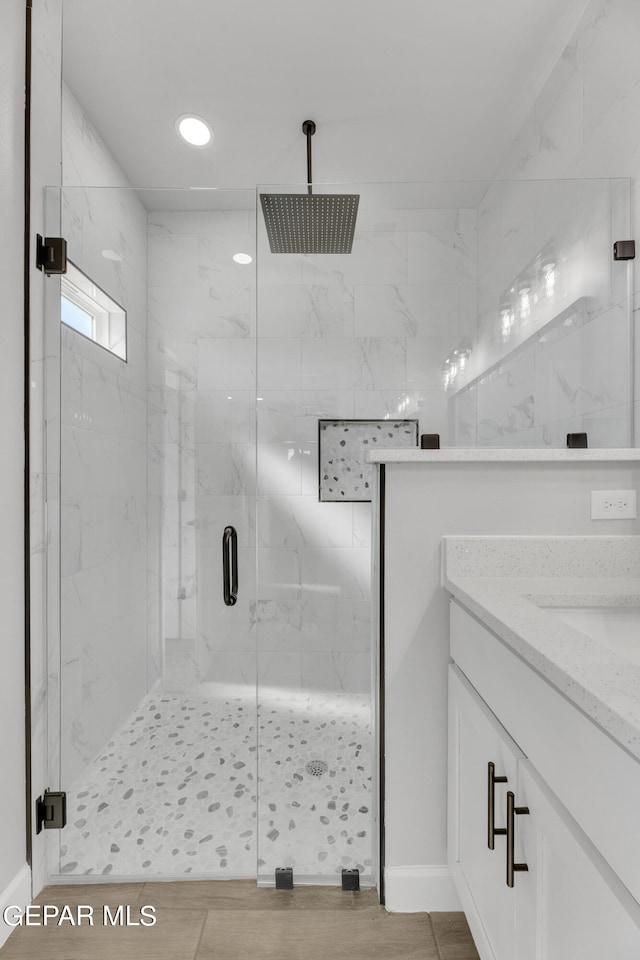 bathroom featuring a shower with door and vanity