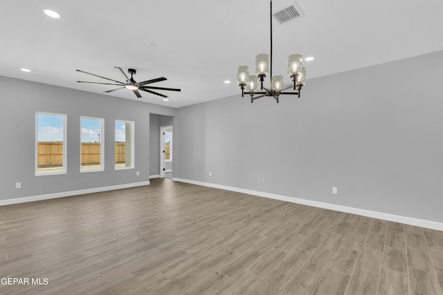 spare room with ceiling fan with notable chandelier and light hardwood / wood-style flooring