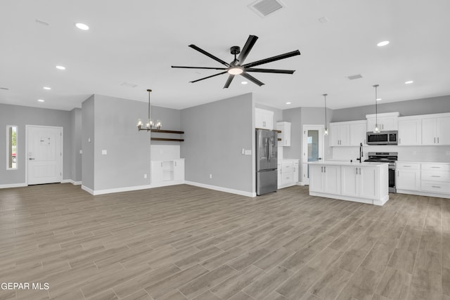 unfurnished living room with sink, ceiling fan with notable chandelier, and light hardwood / wood-style floors