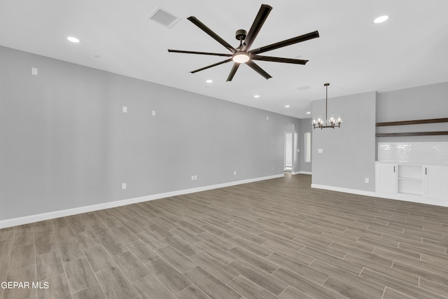 unfurnished living room featuring ceiling fan with notable chandelier and light wood-type flooring