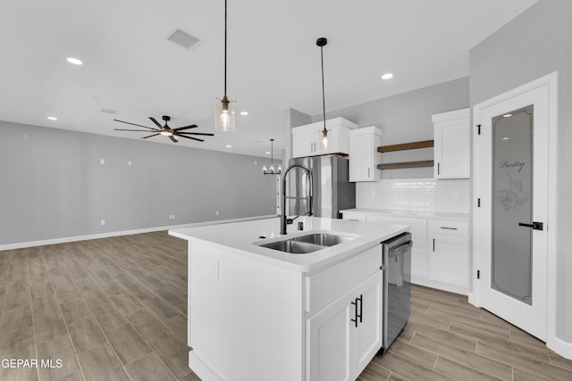 kitchen with an island with sink, stainless steel appliances, white cabinets, sink, and pendant lighting