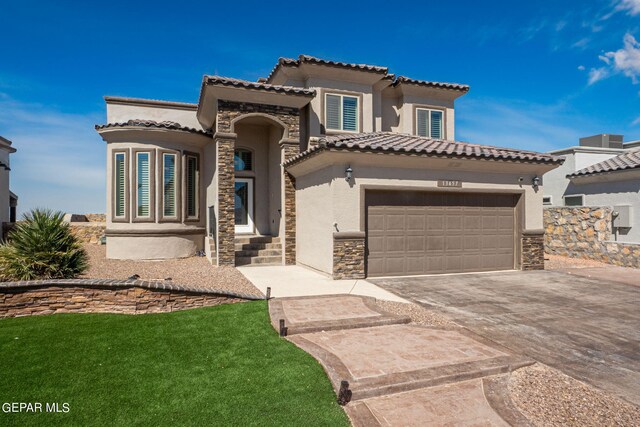 mediterranean / spanish house with a garage and a front lawn