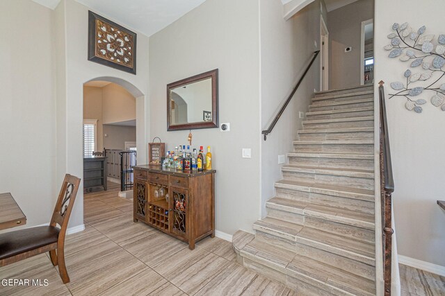 stairs with tile patterned flooring and a towering ceiling